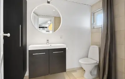 a bathroom with a sink and a toilet and a mirror at Cozy Home In Løgstør With Sauna in Løgstør