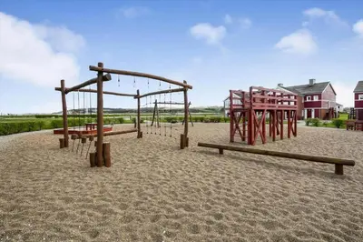 an empty playground with wooden equipment in the sand at G186-Lemvig-Vinkelhagevej-186 in Lemvig
