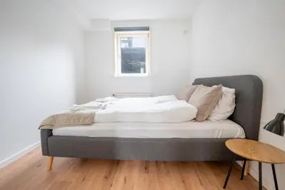 a bedroom with a bed with white sheets and a window at City Apartments in Holstebro