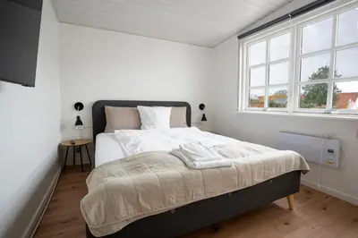 a bedroom with a large bed in a room with windows at City Apartments in Holstebro