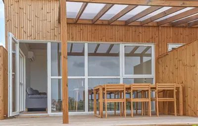 a wooden house with a large window and a table and chairs at Gorgeous Home In Hanstholm With House Sea View in Hanstholm