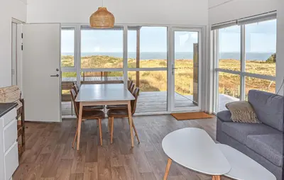 a living room with a table and a couch at Nice Home In Hanstholm With House Sea View in Hanstholm