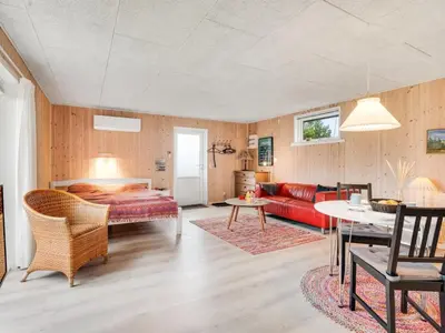 a living room with a bed and a red couch at Holiday Home Tekla - 75m from the sea by Interhome in Thisted
