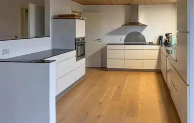 a large kitchen with white cabinets and a wooden floor at Awesome Home In Thisted With House Sea View in Thisted