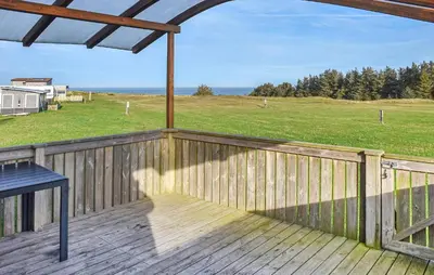 a deck with a table and a view of a field at Beautiful Home In Hanstholm With Swimming Pool in Hanstholm