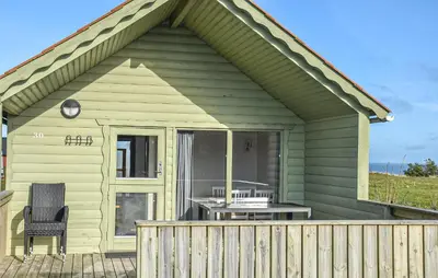 a green house with a table and a chair on a deck at Beautiful Home In Hanstholm With House A Panoramic View in Hanstholm