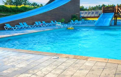 a swimming pool with a slide and chairs in it at Gorgeous Home In Hanstholm With Outdoor Swimming Pool in Hanstholm