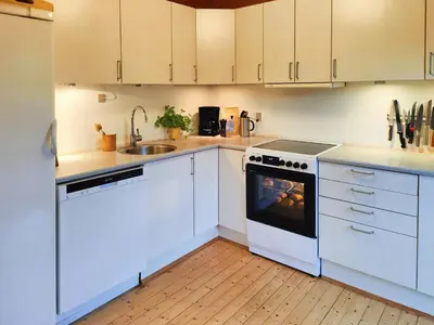 a kitchen with white cabinets and a stove and a sink at Cozy Cottage Close To Thy National Park in Thisted
