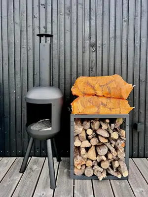 a gray chair sitting next to a pile of fire wood at Summer House Surrounded By Reeds Near Limfjorden in Lemvig
