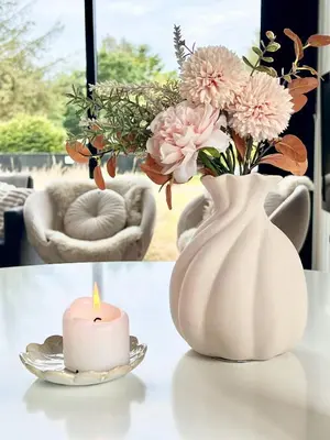 a candle and a vase with flowers on a table at Summer House Surrounded By Reeds Near Limfjorden in Lemvig
