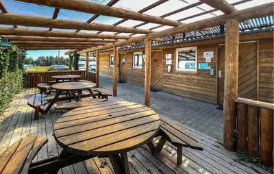 a patio with tables and benches on a wooden deck at 2 Bedroom Stunning Home In Hanstholm in Hanstholm