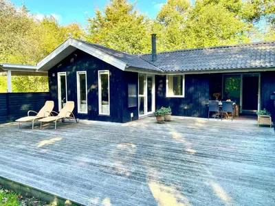 a blue house with two chairs on a wooden deck at Nature Retreat With Fjord Views Near Spøttrup in Spottrup