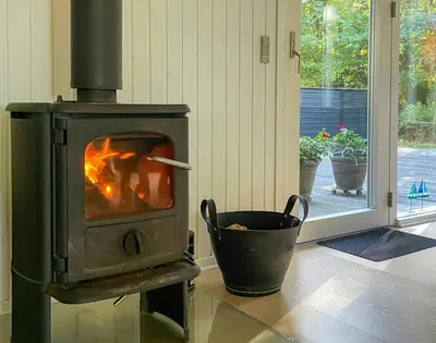 a wood stove in a room with a bucket at Nature Retreat With Fjord Views Near Spøttrup in Spottrup