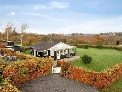 a small house with a white fence in a yard at Holiday Home Hjalma - 250m to the fjord by Interhome in Farsø