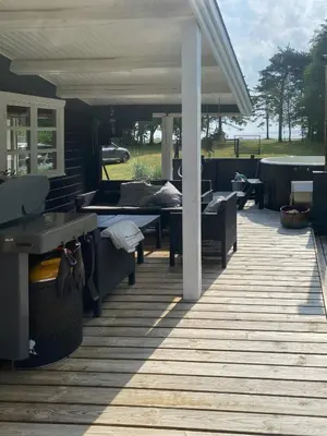 a wooden deck with tables and chairs on a house at Log Cabin With Hot Tub And Fjord View in Viborg