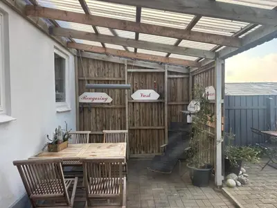 a wooden pergola with a table and chairs on a patio at 4 person holiday home in Hanstholm in Hanstholm