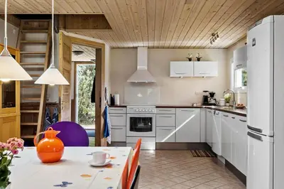 a kitchen with a table and a white refrigerator at JB404-Fjerritslev-Jesper-Jensensvej-9 in Slettestrand