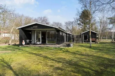 a black house in a field with a grass yard at LF407-Hurup-Thy-Nattergalevej-7 in Sønder Ydby