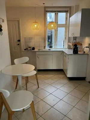 a kitchen with a table and two chairs and a table at Lejlighed midt i Thisted in Thisted