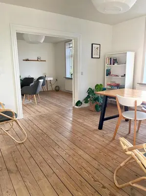 a living room with a table and chairs at Lejlighed midt i Thisted in Thisted
