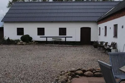 a white building with a picnic table in front of it at Idyllic Countryside Farm with Horseback Riding in Nibe