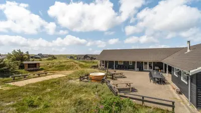 a building with picnic tables and benches in a field at Villavilla 176 - Vrist, Vestjylland in Harboør