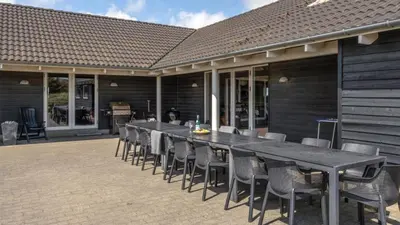 a long table and chairs on a patio at Villavilla 176 - Vrist, Vestjylland in Harboør