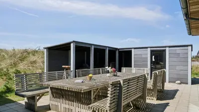 a house with a table and benches on a deck at Villavilla 607 - Vorupør, Nordjylland in Thisted