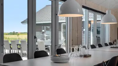 a dining room with tables and chairs and large windows at Villavilla 542 - Hostrup Strand, Limfjorden in Spottrup
