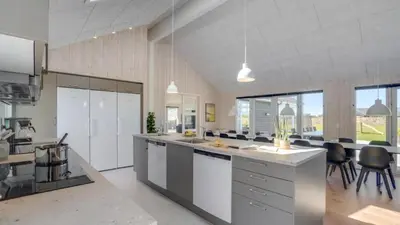 a large kitchen with white counter tops and chairs at Villavilla 542 - Hostrup Strand, Limfjorden in Spottrup
