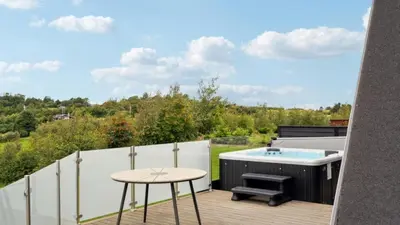 a patio with a hot tub and a table at Villavilla 603 - Hostrup Strand, Limfjorden in Spottrup