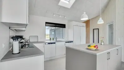a kitchen with white cabinets and a bowl of fruit on the counter at Villavilla 547 - Hostrup Strand, Limfjorden in Spottrup