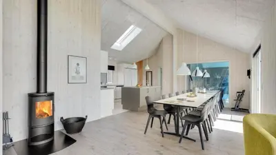 a kitchen and dining room with a fireplace and a table at Villavilla 547 - Hostrup Strand, Limfjorden in Spottrup