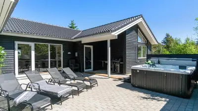 a patio with a hot tub and chairs and a bathtub at Villavilla 494 - Thorup Strand, Nordjylland in Fjerritslev