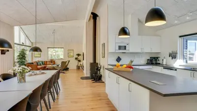 a kitchen and living room with white cabinets and a long counter at Villavilla 494 - Thorup Strand, Nordjylland in Fjerritslev