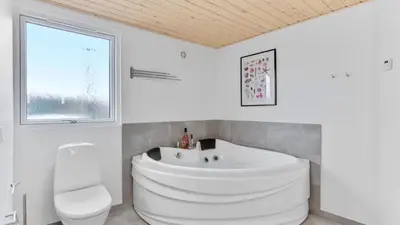 a bathroom with a large white tub and a toilet at Villavilla 539 - Hostrup Strand, Limfjorden in Spottrup