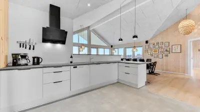 a kitchen with white cabinets and a dining room at Villavilla 539 - Hostrup Strand, Limfjorden in Spottrup