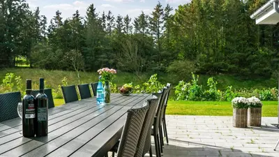 a wooden table with a bottle of wine and chairs at Villavilla 429 - Hostrup Strand, Limfjorden in Spottrup