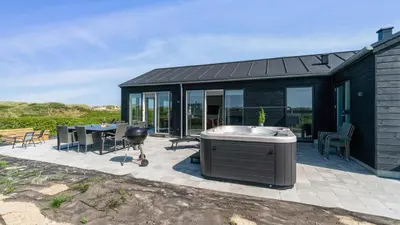 a black house with a hot tub on a patio at Villavilla 514 - Grønhøj, Nordjylland in Løkken