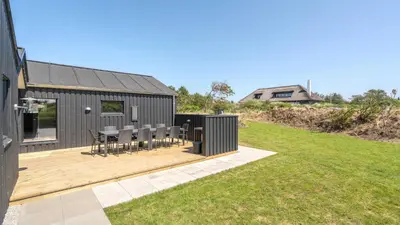a wooden deck with chairs and a house at Villavilla 909 - Blokhus, Nordjylland in Blokhus