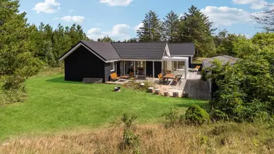 a black house in a field with a yard at Villavilla 691 - Blokhus, Nordjylland in Blokhus