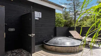 a hot tub on a wooden deck with a chair at Villavilla 691 - Blokhus, Nordjylland in Blokhus