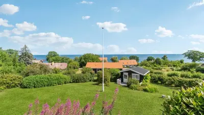 a garden with a house and the ocean in the background at Villavilla 691 - Blokhus, Nordjylland in Blokhus