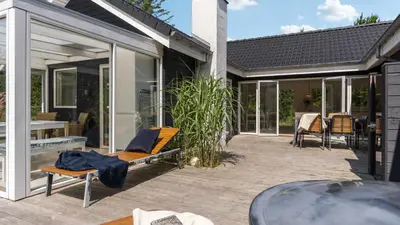 a patio with glass doors and a table at Villavilla 691 - Blokhus, Nordjylland in Blokhus