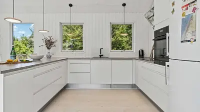 a white kitchen with white cabinets and a refrigerator at Villavilla 691 - Blokhus, Nordjylland in Blokhus