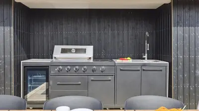 a kitchen with a stove and some chairs at Villavilla 680 - Blokhus, Nordjylland in Blokhus