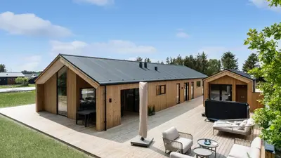 a large wooden house with a deck at Villavilla 683 - Blokhus, Nordjylland in Saltum