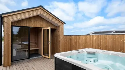 a wooden building with a hot tub on a deck at Villavilla 683 - Blokhus, Nordjylland in Saltum