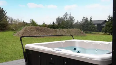 a jacuzzi tub on a porch with a yard at Villavilla 692 - Blokhus, Nordjylland in Blokhus