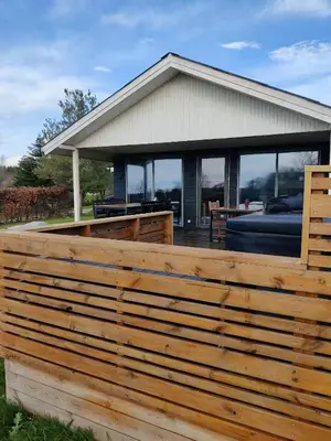 a wooden fence in front of a house at Peaceful Holiday Home With Pool Summer And Spa in Farsø